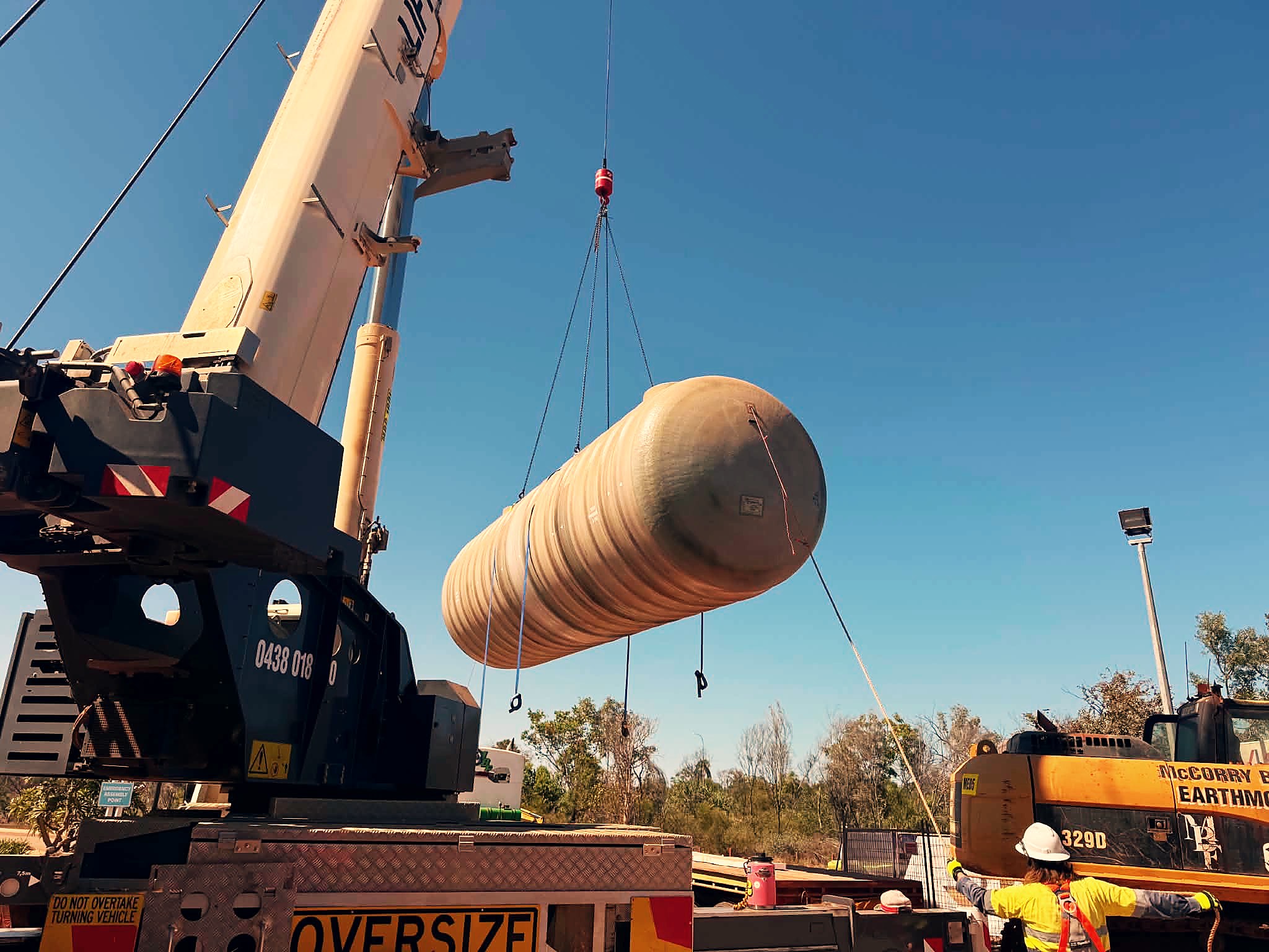 Crane lifting an underground fuel tank into place on a fuel site project